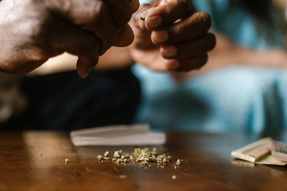 Mano sosteniendo varias semillas de cannabis sobre una mesa de madera para examinarlas antes de germinar